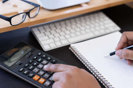 man use calculator  make note with calculate about cost  in office Close upの写真素材