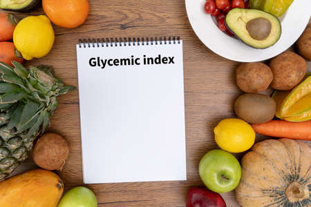 Glycemic index Fitness and weight loss concept, dumbbells, white scale, fruit and tape measure on a wooden table, top viewの写真素材