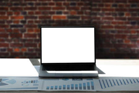 Laptop with blank screen on table interior, man at his workplace using technology