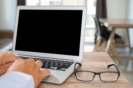 Man of businessman hand working on laptop computer on wooden desk Laptop with blank screen on table.の写真素材