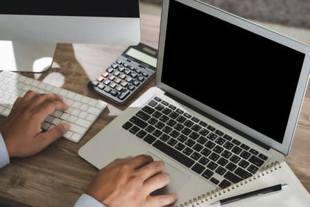 Man of business man hand working on laptop computer on wooden desk Laptop with blank screen on table.の写真素材