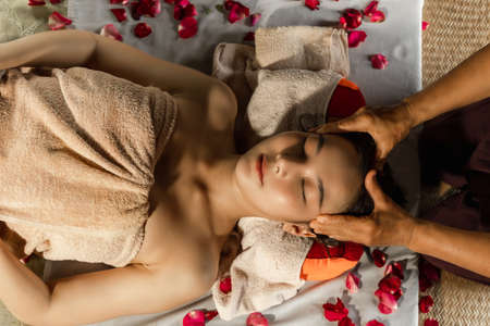 Asian woman enjoying a salt scrub massage at spa. Healthcare spa and massage thai concept  Girl receiving holistic massage treatment thai masseuse woman getting massageの写真素材