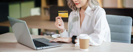 Young beautiful Asian woman smiling and happy, showing presenting credit card online shopping using with mobile phone app pay online copy spaceの写真素材