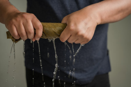 Man's hands squeeze wet fabric, outdoor drop water, short squeezeの写真素材