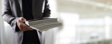 man holding a magazine publication page media stack to stack communication research data to learn advertising and banner space objectsの写真素材