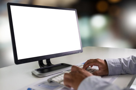 A young businessman is working on the laptop using a desktop computer with a blank screen and an empty copy space display.の写真素材