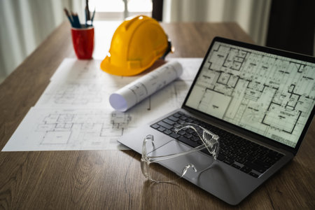 Architecture plans architect paper Clear protective glasses on a notebook computer discussing building plan design and blueprint paper Cropped imageの写真素材