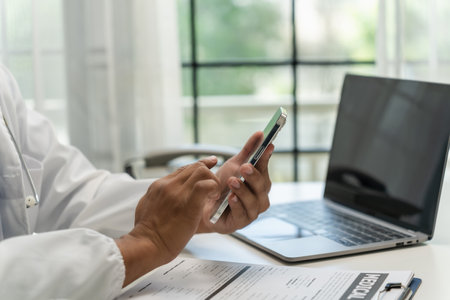 Doctor Smiling working with mobile phones and remote online services at the clinic smart medical doctor high quality service conceptの写真素材