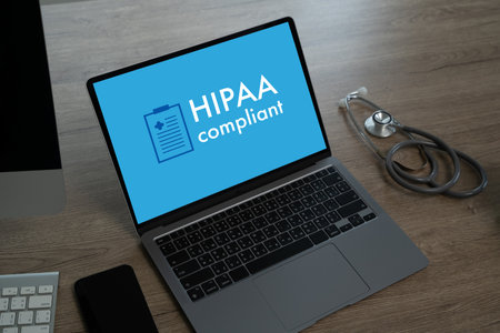 A laptop with HIPAA compliant on it. A stethoscope is next to the laptopの写真素材