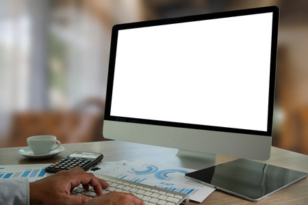 A businessman is using a modern laptop on a white desk in a bright office, typing on a keyboard while viewing a blank screen, showcasing technology and communication.の写真素材