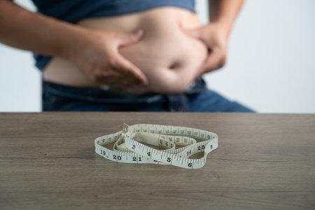 Overeating causes belly fat, tight jeans, and cellulite. A healthy lifestyle and diet improve body shape and wellness. Man wants to lose weight.の写真素材