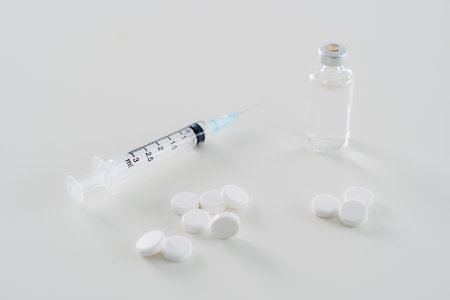 A syringe and a bottle of pills are on a white table. Concept of caution and responsibilityの写真素材
