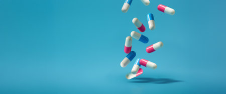 Falling pills on a blue background. Antibiotics A blue and pink pill is falling On a Isolated Blue Backgroundの写真素材