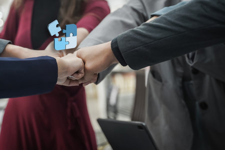 A team collaboration with hands group businesspeople shaking hands with puzzle pieces floating above, symbolizing teamwork and collaborationの写真素材