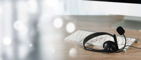 An all center and customer service computer desk with headset and keyboard workspace setup for customer service or online communication modern officeの写真素材