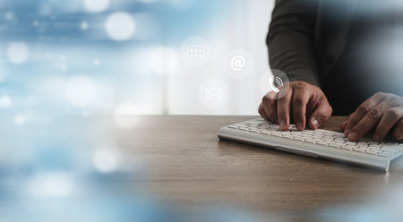 A call center person typing wireless keyboard with digital communication icons floating above, representing online communication and digitalの写真素材