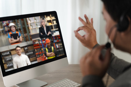 A virtual meeting person participating virtual meeting computer screen making ok gesture with hand wearing headset home or office setting showingの写真素材