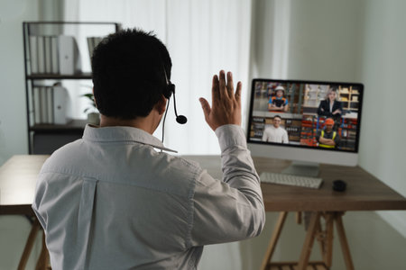 A virtual meeting and virtual conference man white shirt participating virtual meeting computer waving to screen with multiple people video callの写真素材