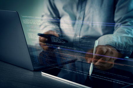 A programming code on representing person working laptop with digital code and tablet, using stylus, modern workspace, focused technologyの写真素材