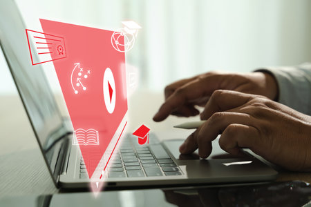 An educational video person using laptop with digital educational icons and graphics floating above keyboard, symbolizing online learning and digitalの写真素材