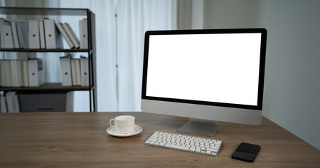 A computer with blank screen on table modern workspace with sleek computer, keyboard, smartphone, and coffee cup wooden desk, creating professionalの写真素材