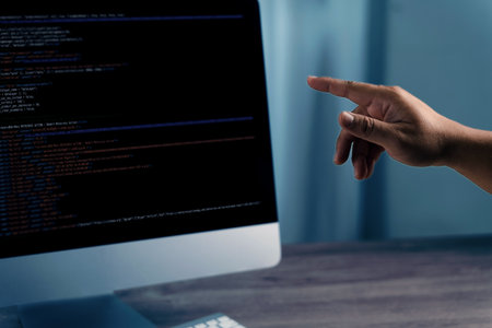 A programming code on representing person pointing computer screen displaying code, indicating programming or software development activityの写真素材