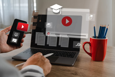 An educational video person using smartphone and laptop to watch and manage online video content, with digital icons and documents floating aboveの写真素材