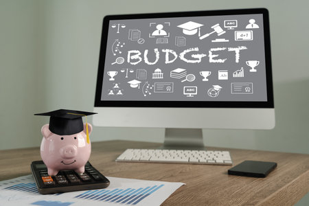 Student plan computer monitor displaying word BUDGET with educational icons, piggy bank wearing graduation cap calculator, and financialの写真素材