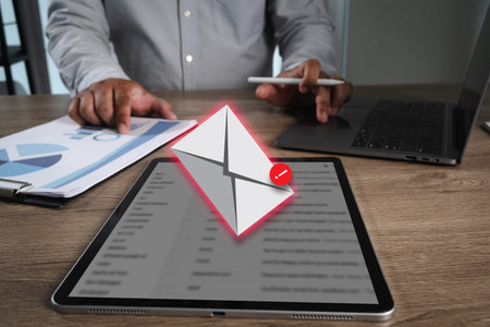 Phishing mail person working desk with tablet displaying email notification, laptop, and documents...