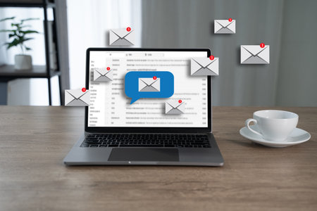 Email communication concept shown through notification icons flying around a laptop screen,...