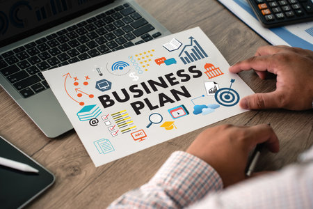Business plan sheet on office desk with laptop and calculator, featuring strategy target, analytics, checklist, growth ideal for startup planning, corporate strategy, marketing.の写真素材