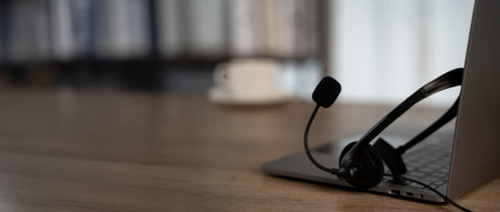 Professional office mood with headset resting on laptop, natural light and negative space for headlines perfect for hotline, customer success, IT support, and training materials.の写真素材