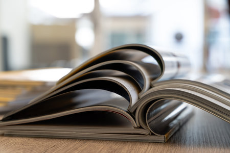 Education and research books and magazine pages stacked on desk, representing learning, reading,...