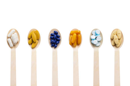 Top view Variety of vitamin and mineral pills in wooden spoon isolated on white background, Dietary...