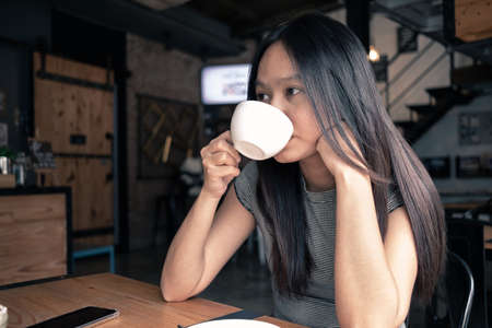 Asia woman drinking coffee in coffee shopの写真素材