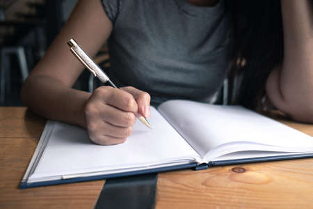 Asia woman writing down her idea on notebook in coffee shopの写真素材