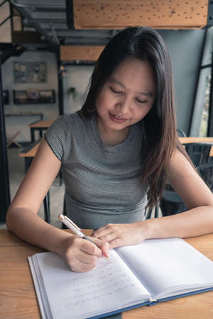 Asia woman writing a book in coffee shopの写真素材