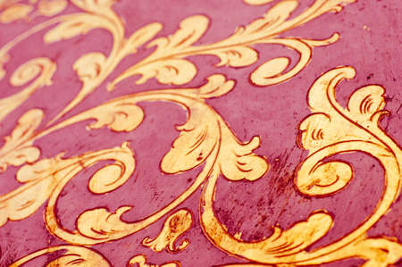 Fourish pattern. Gold leaf floral design on red background. Old, antique surface.の写真素材