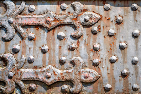 Rusty, studded iron plate. Rivets on old, rusty, metal door. Weathered, aged, grunge texture.  Fleur de lis design.の写真素材