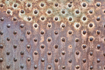 Rusty metal texture. Studded iron plate. Rivets on old, rusty, metal door. Weathered, aged, grunge texture.の写真素材