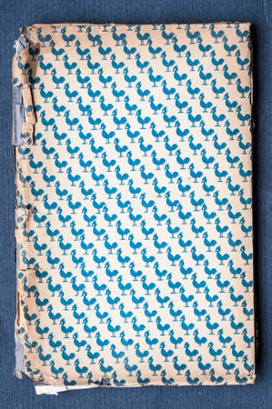 Close-up of an old book with a blue and white patterned paper cover. Worn edges suggest age and use.の写真素材