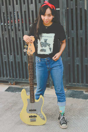 smilling young asian woman playing electric bass guitar in casual styleの写真素材