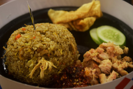 Fried rice with shredded chicken and red chili sauce is served on a wooden table in a restaurantの写真素材