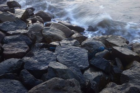 Large boulders hit by the waves around the beach, one of the tourist cities of Tegal, Indonesia, which is often called "Pantai Alam Indah" or "PAI"の写真素材