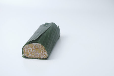 A raw food made from soybean seeds or some other ingredients that are processed through fermentation. This raw food wrapped in banana leaves is called "Tempe" in Indonesian. Isolated Whiteの写真素材