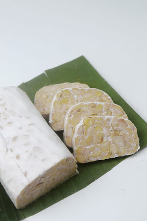Close up photo of several pieces of raw food made from fermented soybeans and yeast and wrapped in banana leaves. in Indonesia this food is often called "Tempe". Isolated whiteの写真素材