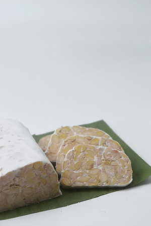 Close up photo of several pieces of raw food made from fermented soybeans and yeast and wrapped in...