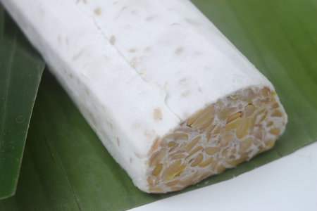 A raw food made from fermented soybeans and yeast and wrapped in banana leaves. in Indonesia this food is often called "Tempe". Isolated whiteの写真素材