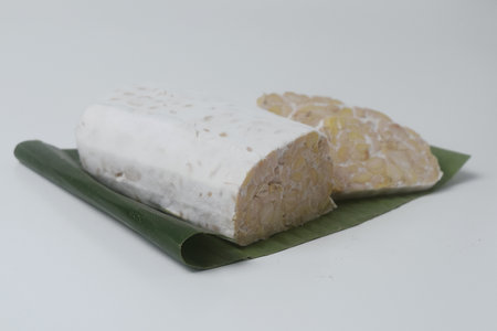 A few pieces of raw food made from fermented soybeans and yeast and wrapped in banana leaves. in Indonesia this food is often called "Tempe". Isolated whiteの写真素材