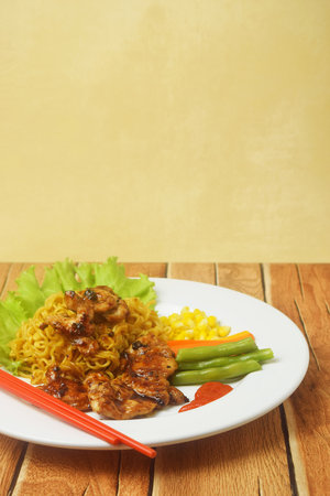 Fried noodles with black pepper seasoned Chicken Steak look tempting on a wooden table. this food is a very unique blend but the taste is very extraordinaryの写真素材